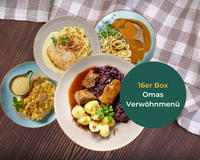 Vier deutsche Gerichte auf Tellern neben einem Tuch mit dem Text „Omas Verwöhnmenü von HOFMANNs“.