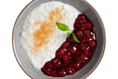 Eine Schale Hofmanns Shop Milchreis mit Kirschsauce, Zimt und einem Zweig Minze.