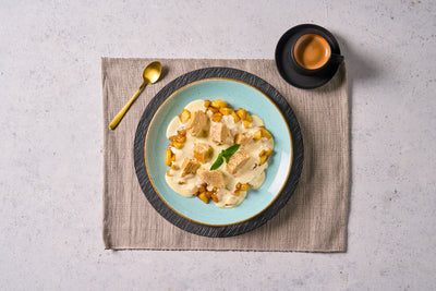 Cremiges Dessert mit Brotwürfeln auf einem blauen Teller - ideal für Ihre Hofmanns Shop Last Chance-Box Wintermomente.