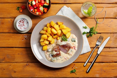Feinschmecker-Box von HOFMANNs: Steak, Sahnesauce, Kartoffeln & Salat rustikal serviert.