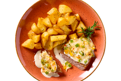 Gewürfelte Patatas Bravas mit Hofmanns Shop Hacksteak "Chili + Cheese", Sahnesauce und Kräutern.