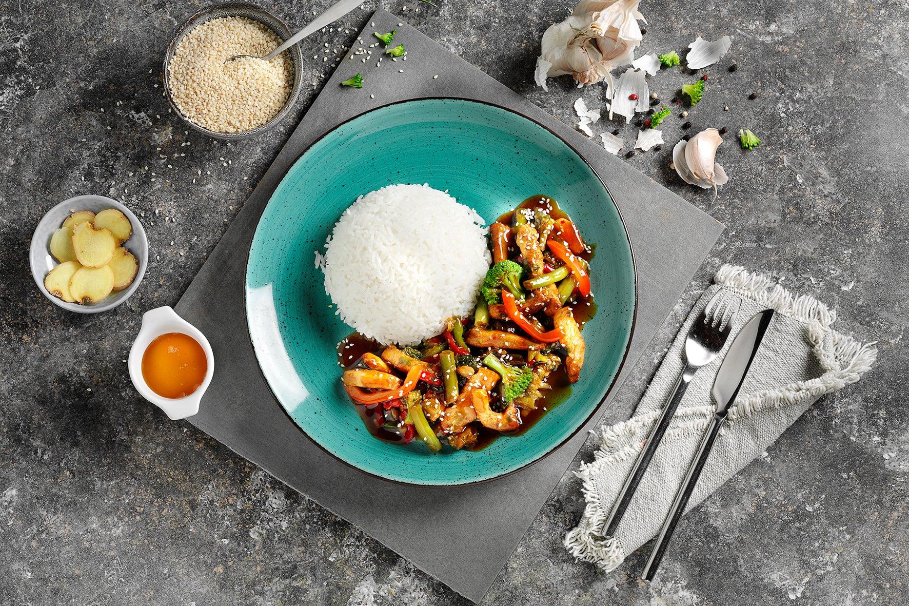 Ein Teller Reis und Gemüse mit Soße, dazu HOFMANNs Asiatische Genussreise Bami Goreng.