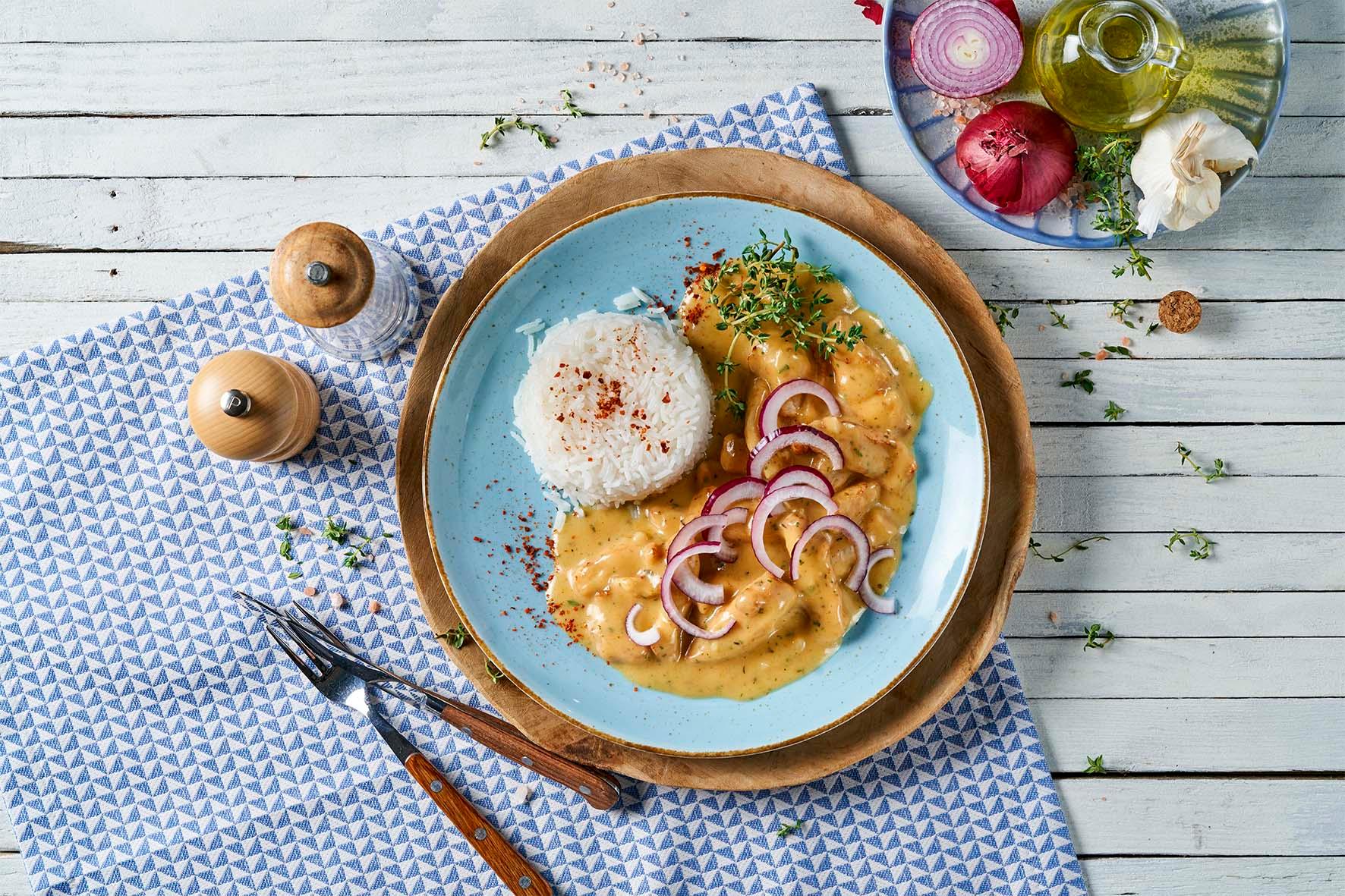 HOFMANNs Klassiker aus aller Welt: Reis mit cremiger Hühnersauce, garniert mit Zwiebeln und Kräutern.