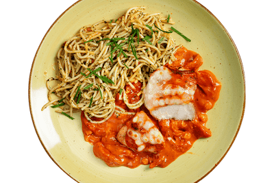 Teller mit mediterranen Kräuter-Spaghetti mit Hofmanns Shop Hähnchenbrust „Caprese“ in Tomatensauce.