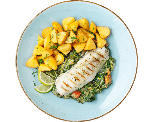 Gegrilltes Alaska-Seelachsfilet von Hofmanns Shop mit Kartoffeln, Gemüse und Limettenscheiben.