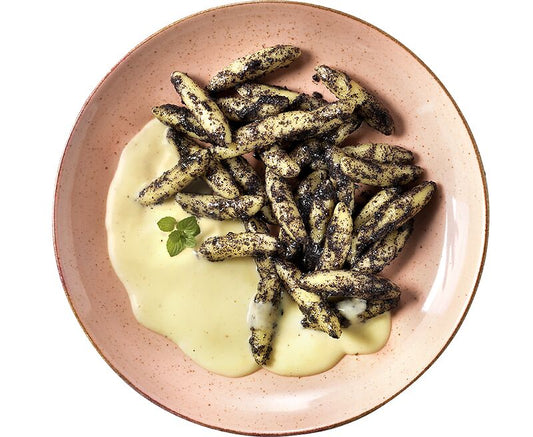 Hofmanns Shop Mohnnudeln serviert mit cremiger Vanillesoße und einem Minzblatt als Garnitur.