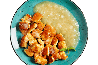 Goldener Kaiserschmarrn mit Apfelkompott von Hofmanns Shop, serviert auf einem türkisfarbenen Teller.