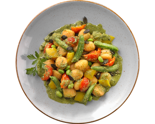 Ein Teller Süßkartoffel-Gnocchi mit Erbsenpesto von Hofmanns Shop, dazu gemischtes Gemüse und garniert mit Petersilie.