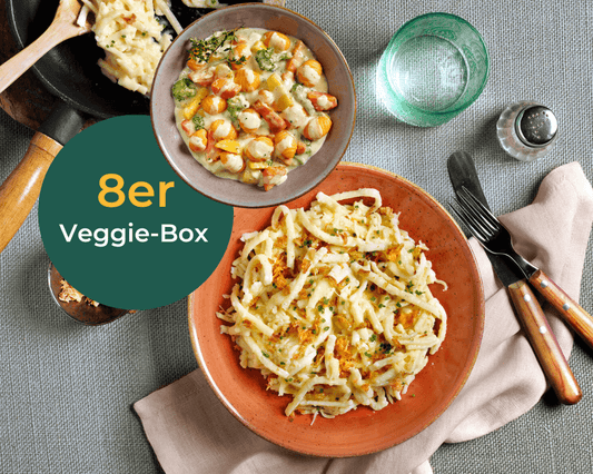 Teller mit HOFMANNs Veggie-Box Käsespätzle und gemischtem Gemüse mit „Veggie-Box“-Auflage.