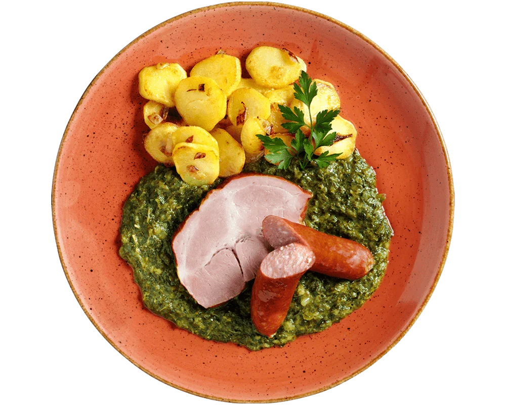 Ein Teller mit HOFMANNs Grünkohl „Norddeutsche Art“, Würstchen, Bratkartoffeln und cremigem Spinat.