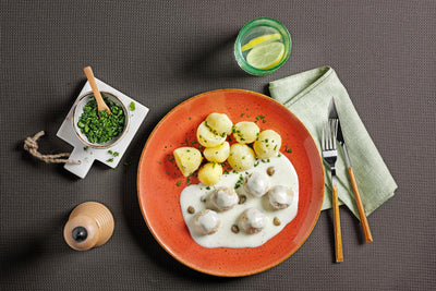 Genießen Sie HOFMANNs Hausmannskost-Box + Dessert-Box: Frikadellen, Kartoffeln, Kräuter und Zitronenwasser.