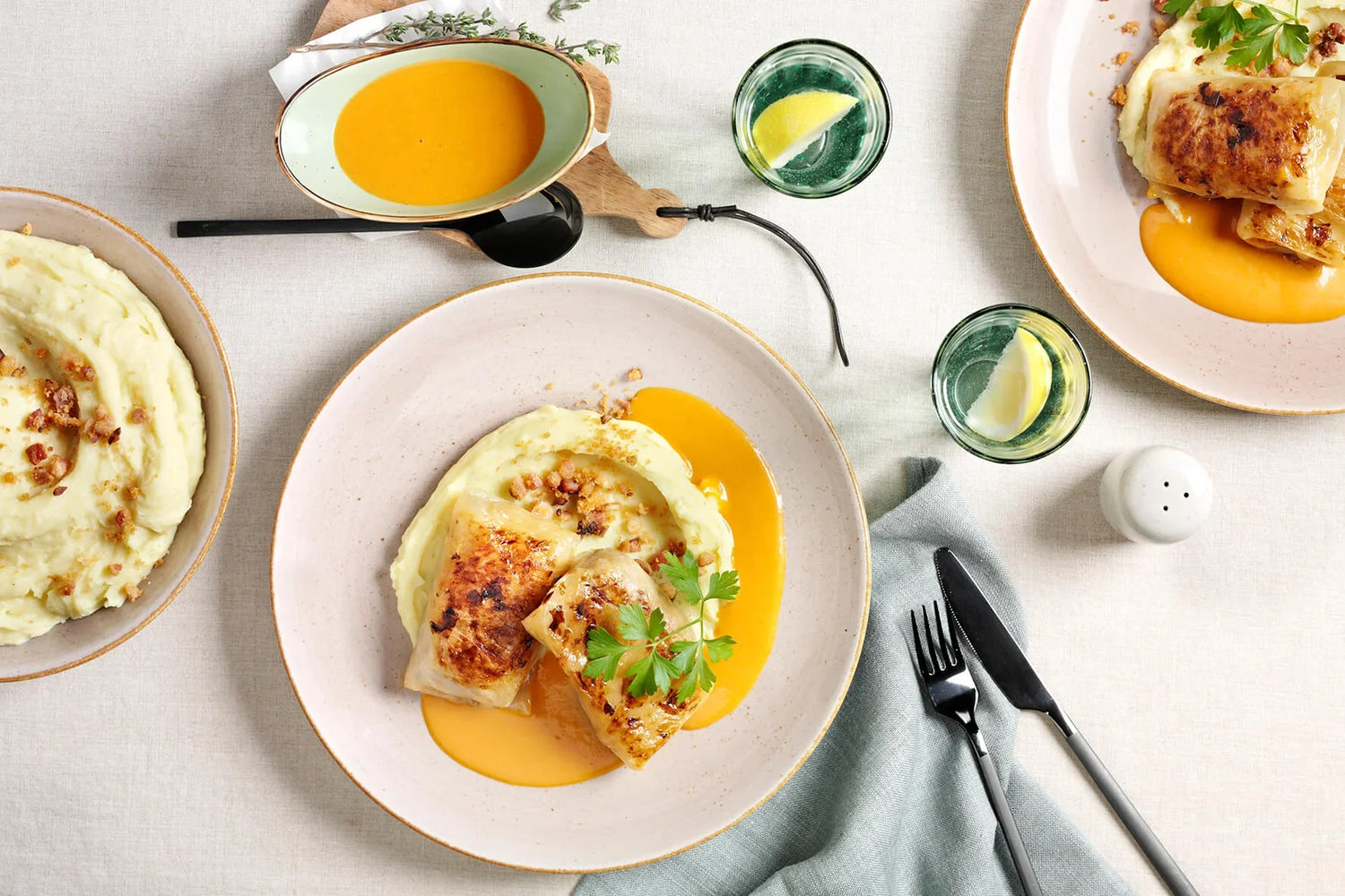 Zwei Kohlrouladen von HOFMANNs mit Kartoffelpüree und Orangensauce, dazu Wasser mit Zitrone.