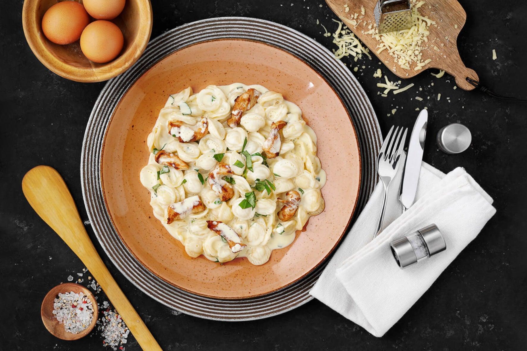 Hofmanns Shop Carbonara vom Huhn: cremige Hühnernudeln mit Kräutern, Pecorino-Käse und Utensilien.