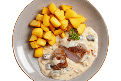 Gebratenes Lammhüftsteak von Hofmanns Shop mit Beilage und Gemüse auf dem Teller serviert.