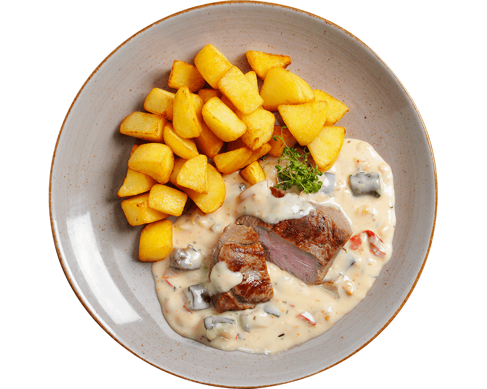 Gebratenes Lammhüftsteak von Hofmanns Shop mit Beilage und Gemüse auf dem Teller serviert.