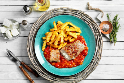 Blauer Teller mit Hofmanns Shop Hackroulade „Griechische Art“, Crinkle Pommes und Tomatensoße.
