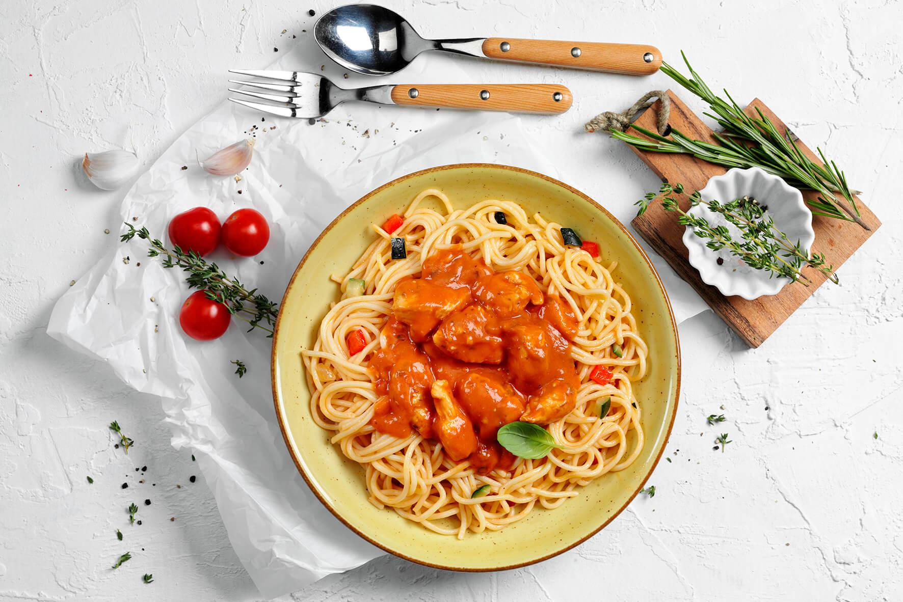 Ein Teller Fit & Free-Box 2.0 von HOFMANNs: Spaghetti, Tomatensoße, proteinreiches Hähnchen, Kräuter.