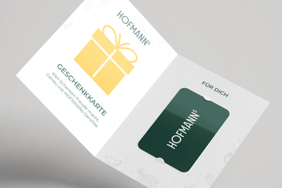 Offener Kartenhalter mit gelbem Geschenksymbol und grüner HOFMANNs Geschenkkarte aus dem Hofmanns Shop darin.
