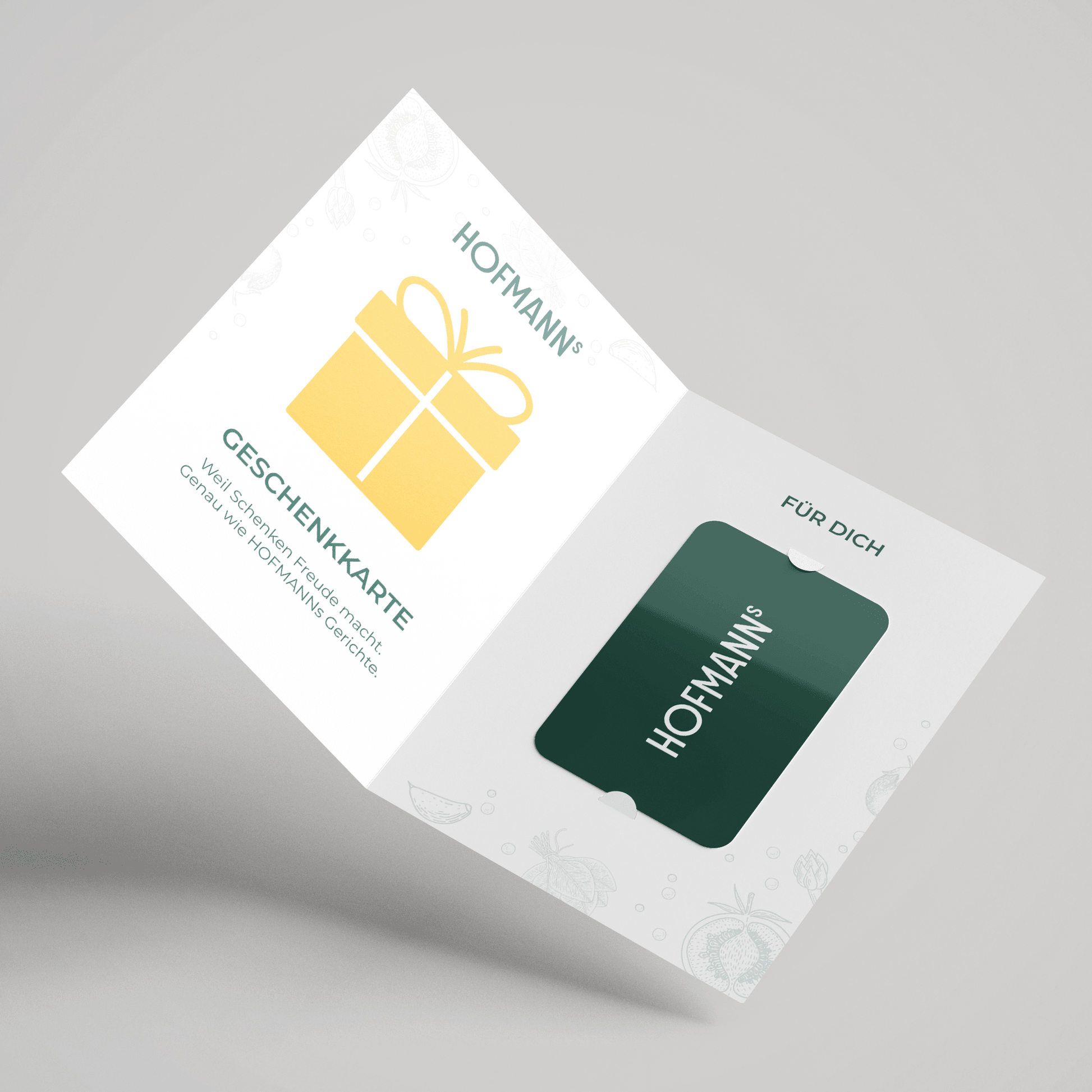 Offener Kartenhalter mit gelbem Geschenksymbol und grüner HOFMANNs Geschenkkarte aus dem Hofmanns Shop darin.