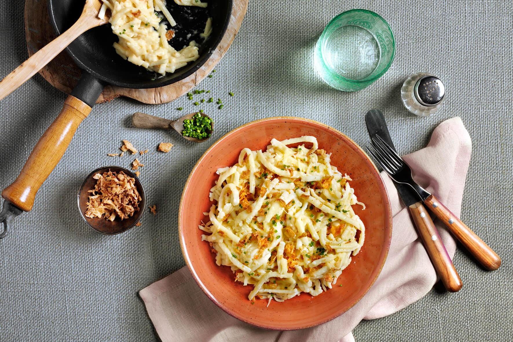 Eine Schüssel BIO Herzhafte Käsespätzle* von Hofmanns Shop, garniert mit Schnittlauch und Röstzwiebeln.