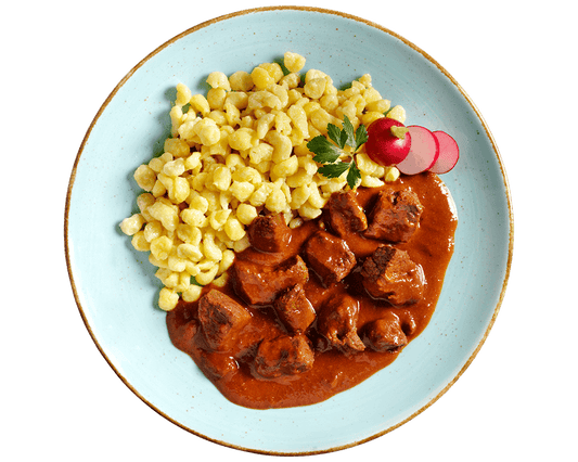 Hofmanns Shop Rindsgulasch serviert mit gelben Knödeln, Petersilie und Radieschenscheiben.