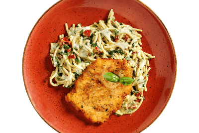 Hofmanns Shop Schnitzel à la Carbonara mit Spinat-Spaghetti, serviert auf einem roten Teller mit Basilikum.