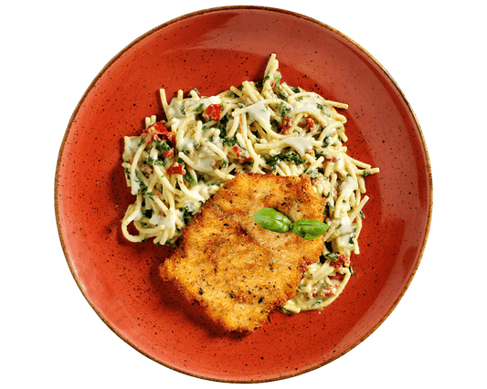 Hofmanns Shop Schnitzel à la Carbonara mit Spinat-Spaghetti, serviert auf einem roten Teller mit Basilikum.