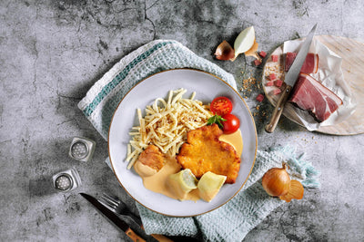 Hausmannskost-Box von HOFMANNs: Teller mit Schnitzel, Pommes, Soße, Tomate; Rinderrouladenseite.